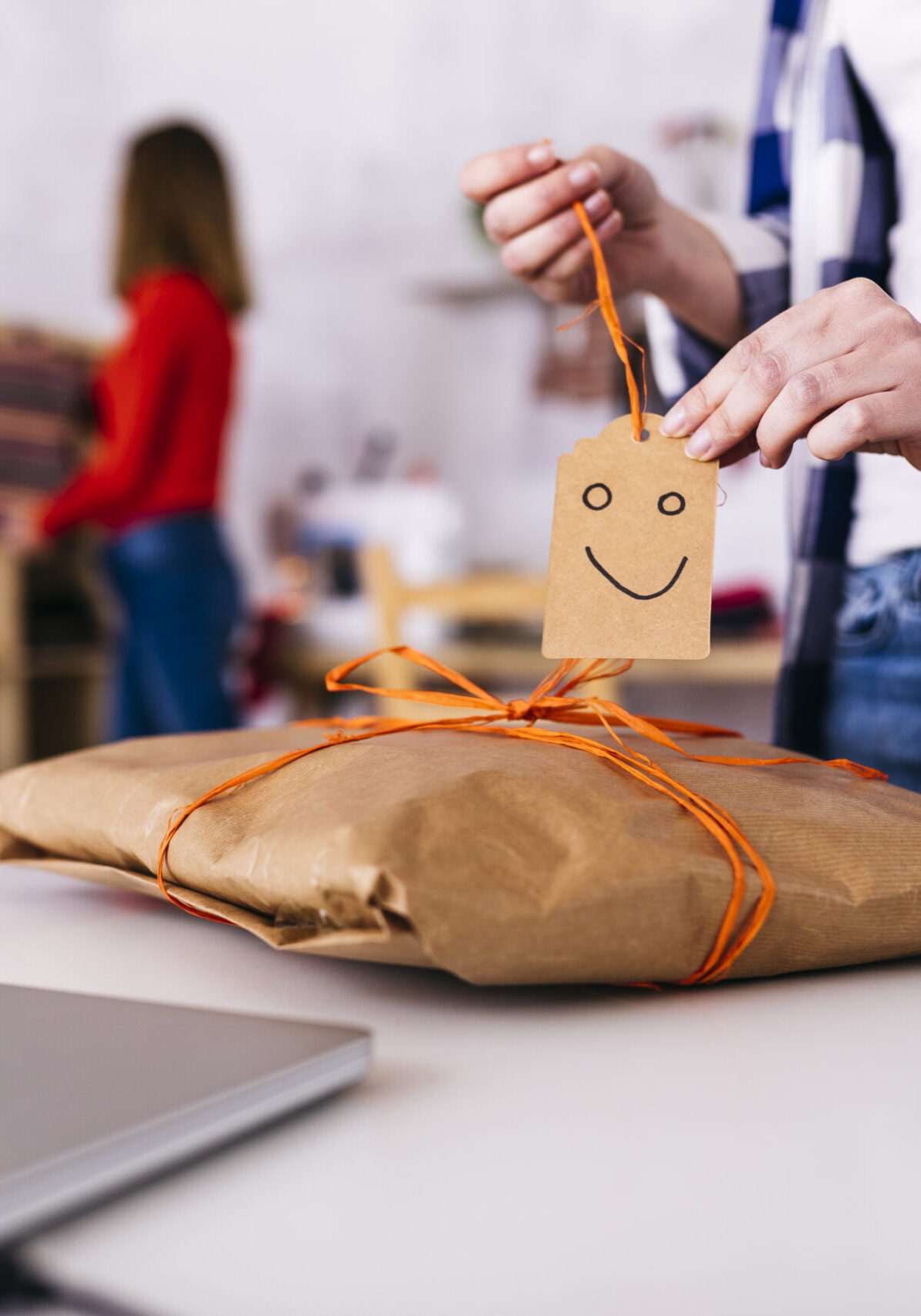 Close-up of fashion designer wrapping a package in studio with smiley face